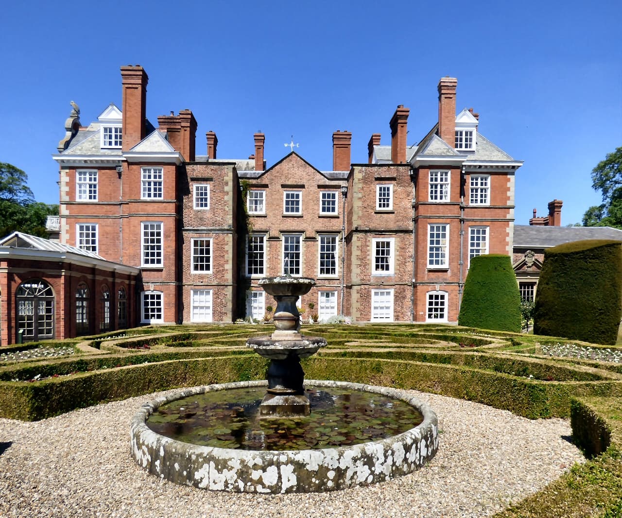The red-brick frontage and box-hedge parterre garden of Bodrhyddan Hall