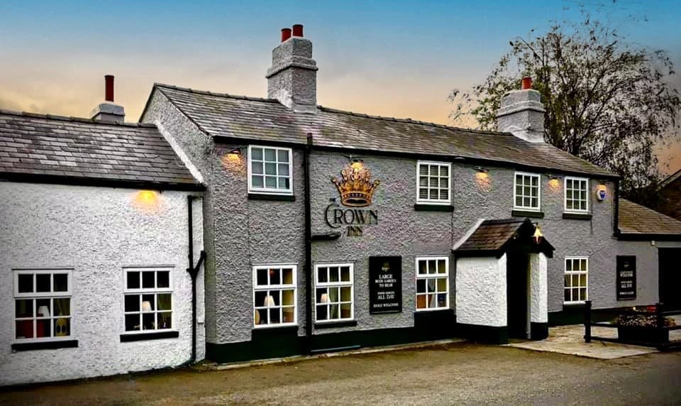 The Crown Inn at dusk, a whitewashed Welsh village pub with lit windows