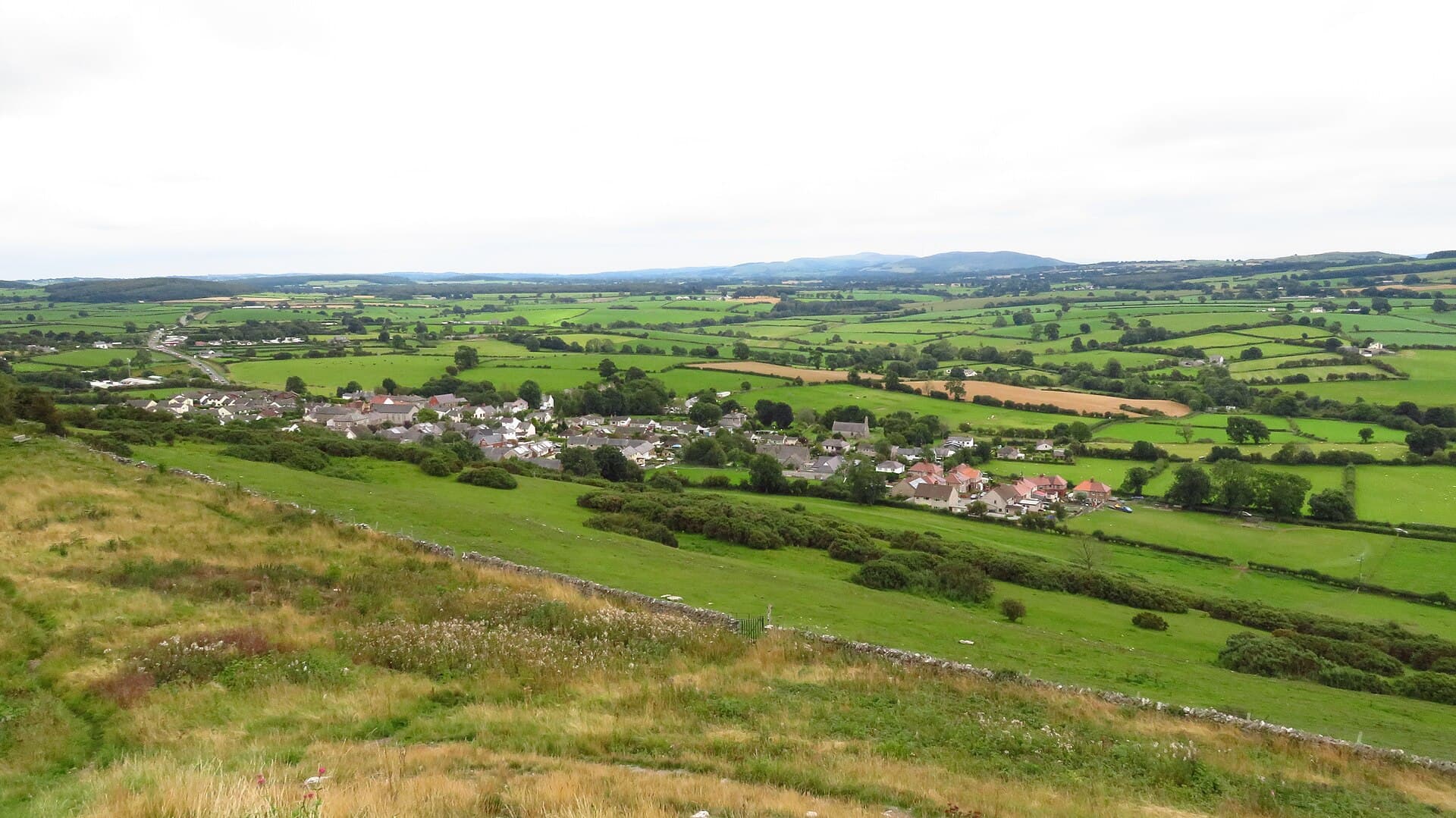 The wide view over green countryside and the village of Trelawnyd from Gop Hill