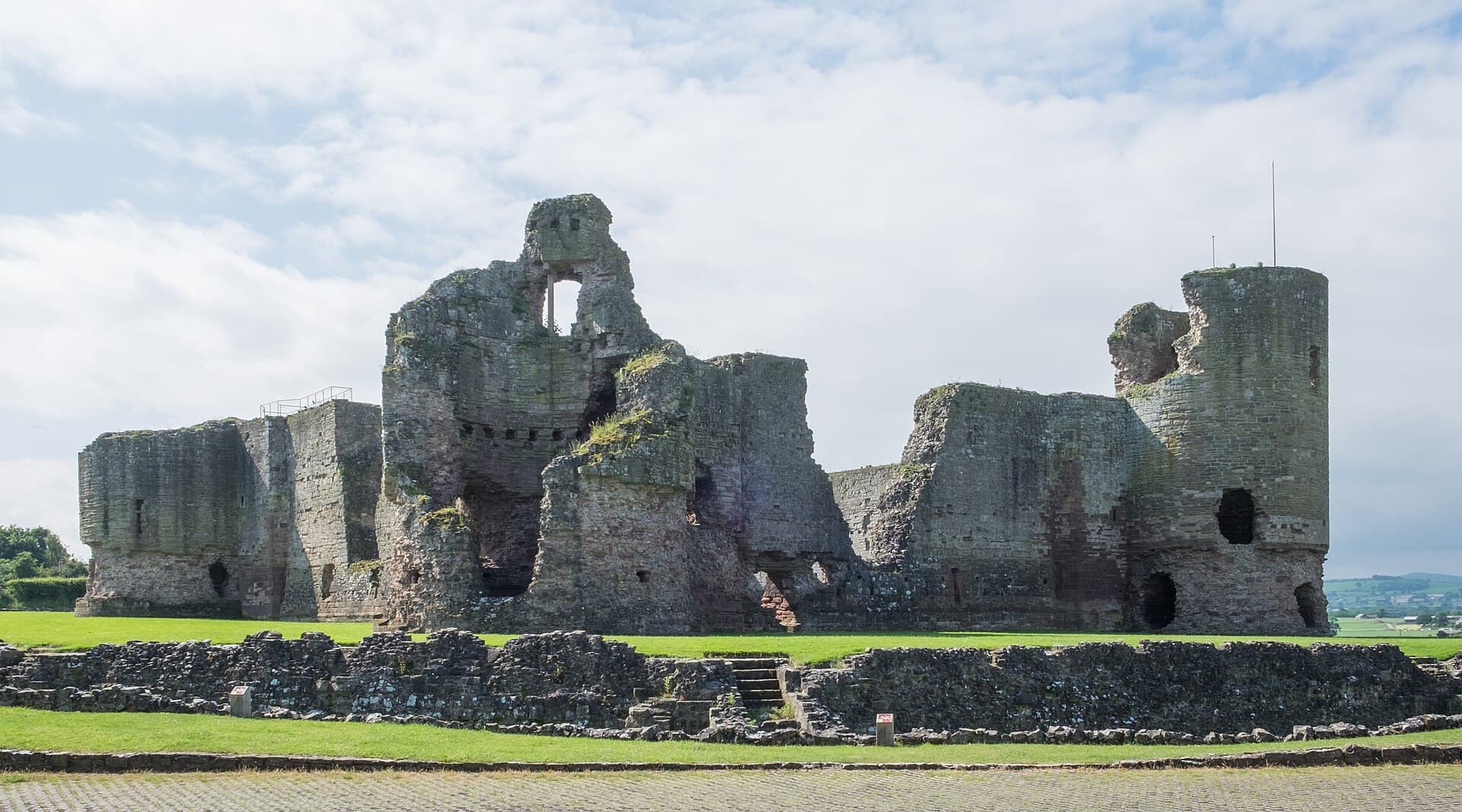 The ruined towers and walls of Rhuddlan Castle on its green riverside mound