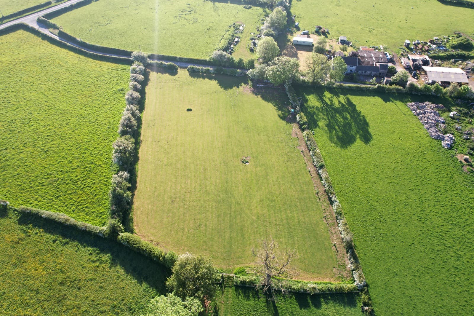 Aerial view of the campsite, a neat green field bounded by hedgerows with the farm buildings alongside